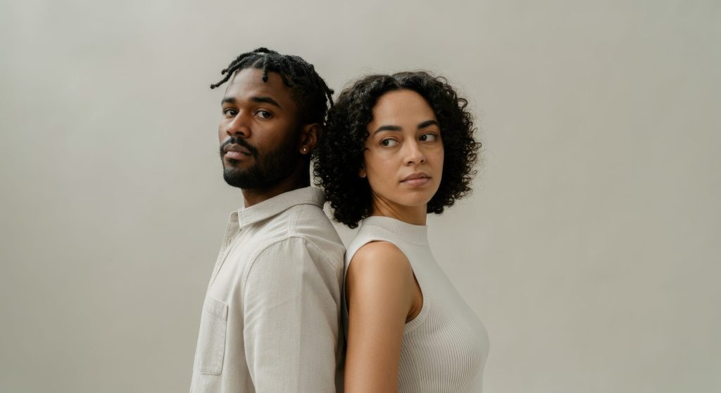 Black male and Hispanic woman standing back to back, looking away, in neutral tones Black male and Hispanic woman standing back to back, looking away, in neutral tones